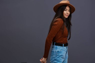 Şapkalı, kahverengi süveterli, rahat bir şekilde poz veren genç bir kadın. Yüksek kalite fotoğraf