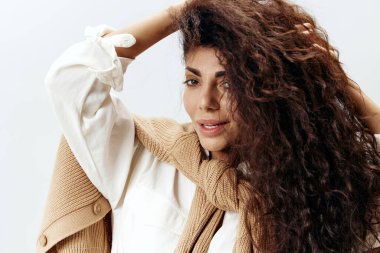 Beyaz Stüdyo Duvarı 'nda izole edilmiş Pastel Sıcak Kazaklı Güzel Latin Kadın ve Beyaz Gömlekli Dokunmatik Kuru Saçlı Poz' un yakın portresi. Moda Mevsimsel Satış Yeni Koleksiyon Kavramı.