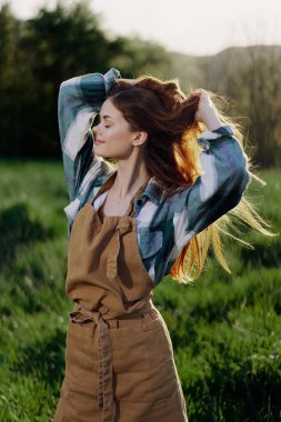 Bir yaz günü, batan güneşin altında, çiftçi ve bahçıvan gibi giyinmiş güzel bir gülümsemeyle genç bir kızın portresi. Yüksek kalite fotoğraf