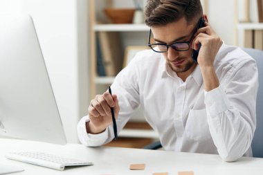 Gözlüklü yakışıklı işadamı masa başında oturuyor ve teknolojiler üzerinde çalışıyordu. Yüksek kalite fotoğraf