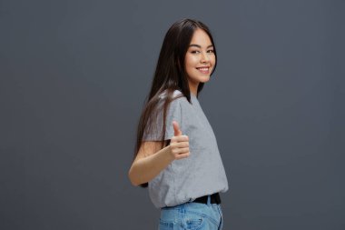 Tişörtlü ve kot pantolonlu bir kadın gençlik tarzı pozu veriyor. Yüksek kalite fotoğraf