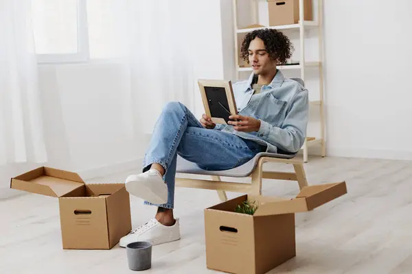 portrait of a man sitting on a chair unpacking with box in hand moving Lifestyle. High quality photo