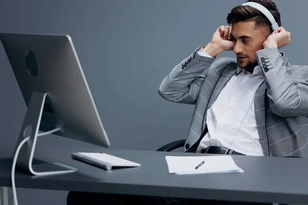 handsome man working at the computer in headphones in the office isolated background. High quality photo