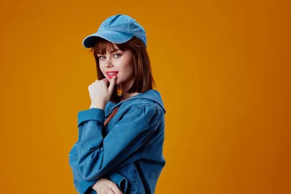 Pretty young female denim cap red lips glamor fashion yellow background unaltered. High quality photo