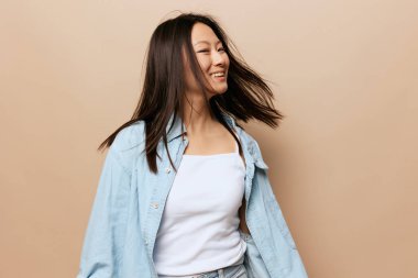 Dans eden, bronz tenli, tapılası genç Asyalı bayan saçlarını sallayarak bej renkli pastel arka planda izole bir şekilde duruyor. İnsanlar ve Duygular. Mutluluk kavramı. Alan Teklif Sancağını Kopyala.