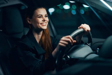 Mutlu, neşeli bir kadın emniyet kemeri takılı bir arabanın direksiyonunda oturuyor ve mutlu bir şekilde yola bakıyor. Yüksek kalite fotoğraf