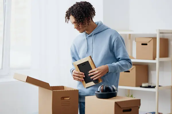 handsome guy cardboard boxes in the room unpacking sorting things out. High quality photo