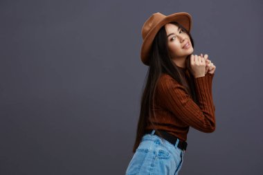 Şapkalı, kahverengi süveterli, rahat bir şekilde poz veren genç bir kadın. Yüksek kalite fotoğraf