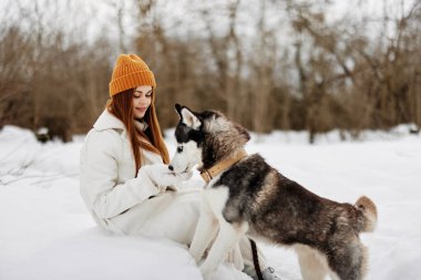 Kış tatilinde köpeğiyle birlikte bir tarlada yürüyüş yapan mutlu genç bir kadın. Yüksek kalite fotoğraf