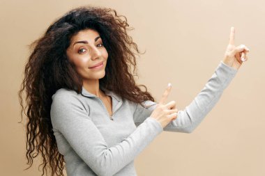 Sıradan giyinmiş genç Afrikalı Amerikalı bir kadın pastel bej duvar arka plan stüdyo portresinde izole edilmiş bir şekilde parmağını kaldırıyor. Büyük indirim ya da tanıtım konsepti. Kopyalama alanı oluşturun, reklam için harika bir teklif