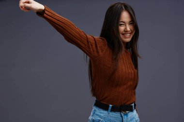 Güzel bir kadın eğlenceli kahverengi süveter giyip izole bir arka plan giyiyor. Yüksek kalite fotoğraf