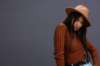 Güzel kadın kahverengi şapkalı el, kahverengi süveter giyer. Gri arka plan. Yüksek kalite fotoğraf