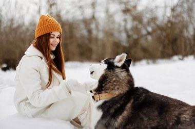 Kışın bir tarlada bir köpekle yürüyüş yapan neşeli bir kadın. Yüksek kalite fotoğraf