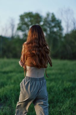 Bir kadın spor yaparken parkta yeşil çimlerin üzerinde koşuyor. Yüksek kalite fotoğraf