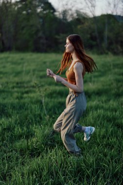 Dışarıda egzersiz yapan ve parkta koşan genç bir kadın. Akşam çimlerin üzerinde gün batımına doğru. Yüksek kalite fotoğraf