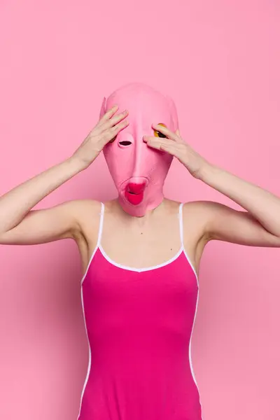 Crazy woman in pink fish head costume poses on pink studio background, provocative Halloween costume. High quality photo