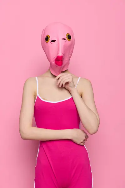 Woman in a fish costume for Halloween poses against a pink background in a crazy scary costume with a pink silicone mask on her head. High quality photo