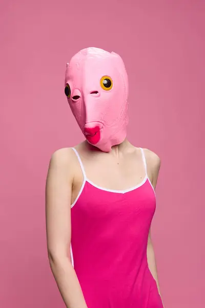 Very strange woman in a pink silicone fish mask for Halloween, crazy image in pink clothes. High quality photo