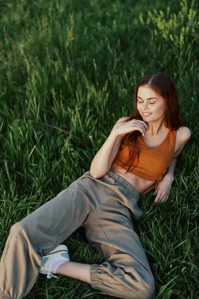 A young happy woman lying relaxed on the grass in the park, the lifestyle of a happy person without depression. High quality photo