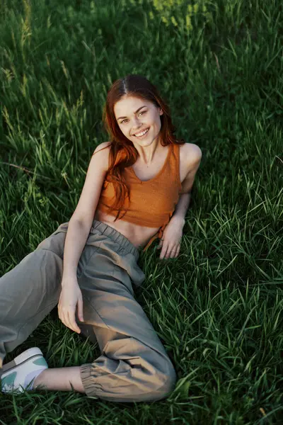 A young happy woman lying relaxed on the grass in the park, the lifestyle of a happy person without depression. High quality photo