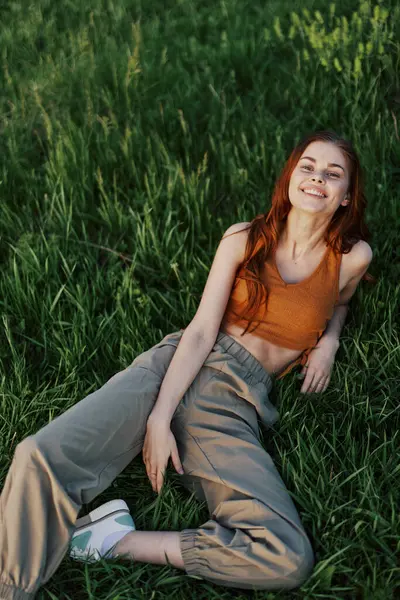 A young happy woman lying relaxed on the grass in the park, the lifestyle of a happy person without depression. High quality photo
