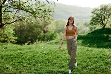 Bir kadın parkta yürüyor, yoga yapıyor ve yaz havasının tadını çıkarıyor. Yaşam tarzı, akıl ve vücut sağlığı hizmetleri. Yüksek kalite fotoğraf