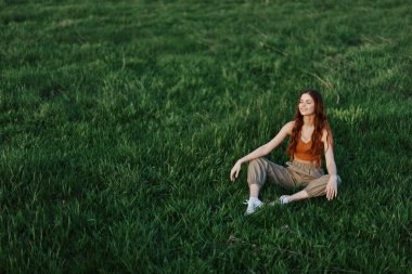 Genç sporcu kadın güneşli bir akşamda parkta çimlerin üzerinde ısınıyor. Yüksek kalite fotoğraf