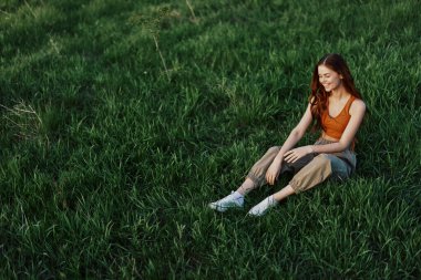 Parkta yeşil çimlerde oturan bir kadın, yukarıdan manzaralı. Yüksek kalite fotoğraf