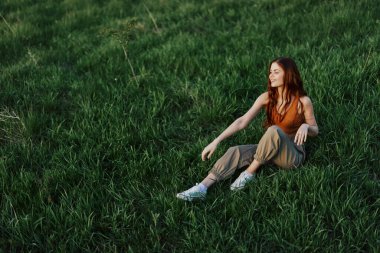 Genç sporcu kadın güneşli bir akşamda parkta çimlerin üzerinde ısınıyor. Yüksek kalite fotoğraf