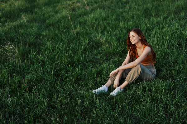 Woman sitting on green grass in nature in a park, view from above. High quality photo