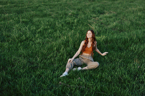 Female student freelancer sits on the grass in the park and watches the sunset, the concept of harmony with the world and nature. High quality photo