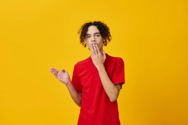 Kırmızı tişörtlü komik beyaz adam sarı stüdyo arka planında yalnız poz veriyor. Reklamcılık için bedava olan en iyi teklif. Günlük kavramlar için duygular