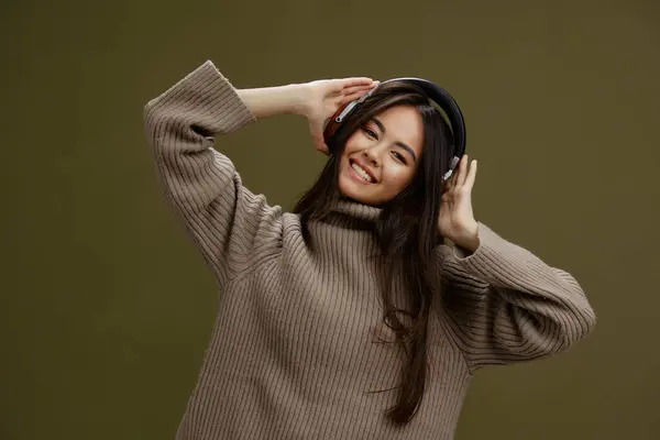 穿着毛衣的女人带着耳机听音乐有趣的绿色背景 高质量的照片 — 图库照片