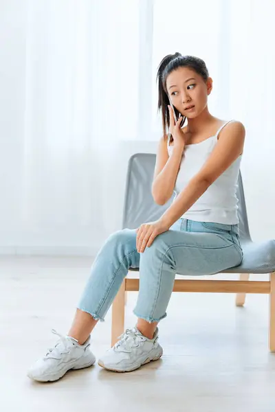 Shocked excited tanned lovely young Asian woman get surprised information in call using phone at home interior living room. Distance communication Social media concept. Cool offer Banner Wide angle