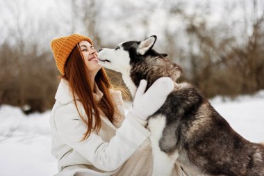 Karda genç bir kadın dışarıda bir köpekle oynuyor arkadaşça bir yaşam tarzı. Yüksek kalite fotoğraf