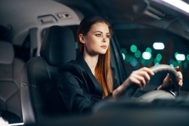 Gece araba sürerken siyah gömlekli hoş bir kadının yatay fotoğrafı. Yüksek kalite fotoğraf