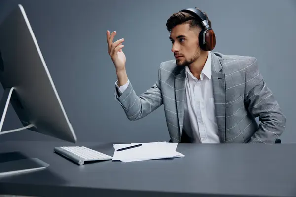 manager in headphones in a gray suit sits in front of a computer executive. High quality photo