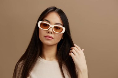 Gözlüklü, bej tişörtlü genç bir kadın. Moda stüdyosu modeli pozu veriyor. Yüksek kalite fotoğraf