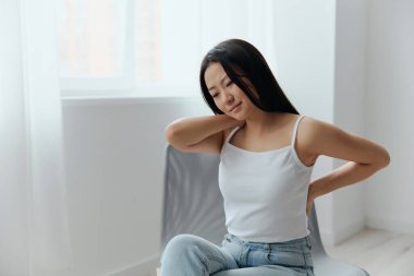 Sırt ağrısı. Uzun bir çalışmadan sonra osteokondrosis 'ten muzdarip olan güzel Asyalı bir kadın ev içi oturma odasında ağrılı beline dokunuyor. Yaralar Kötü Sağlık Hastalığı konsepti. Güzel teklif.