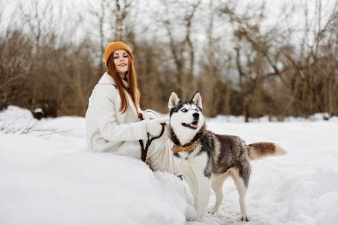 Karda neşeli bir kadın kış tatilinde dışarıda bir köpekle oynuyor. Yüksek kalite fotoğraf