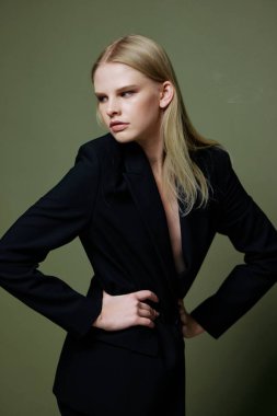 Kendine güvenen bir kız ellerini belinde tutar ve yeşil bir arka planda poz verir. Yüksek kalite fotoğraf