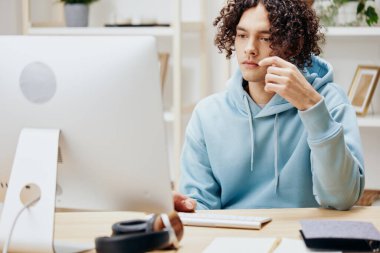 Bir bilgisayar serbest teknolojisinin önünde masada oturan genç bir adam. Yüksek kalite fotoğraf