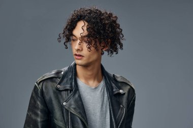 Yakışıklı, şık, bronzlaşmış, deri ceketli adam gri stüdyo arka planında yalnız poz veriyor. Güzel moda teklifi. Büyük Mevsimlik Satış Yeni Koleksiyon konsepti. İlan için alanı kopyala