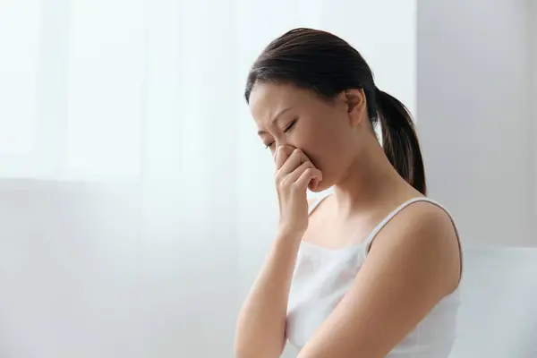 Rhinitis Sinusitis Flu. Suffering tormented tanned beautiful young Asian woman hold hand on nose bridge posing isolated on white background. Injuries Poor health Illness concept. Cool offer