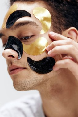 Yüz sağlığı kozmetolojisi cilt bakımında siyah ve altın renkli bir adamın portresi. Yüksek kalite fotoğraf