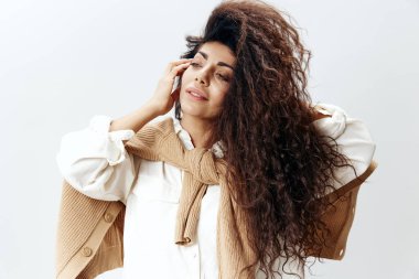 Pastel Sıcak Kazaklı Kıvırcık Latin Kadın ve Beyaz Gömlekli Dokunaklı Yanak Yanağı, Beyaz Stüdyo Duvarında İzole Edilmiş Poz. Moda Mevsimsel Satış Yeni Koleksiyon Kavramı