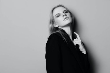 Ceketine dokunan ve kameraya bakan seksi, etkileyici profesyonel model. Stüdyoda poz veren güzel sarışın kadın. Moda markaları için iyi bir teklif. Minimalist sanat tarzı. Yüksek kalite fotoğraf