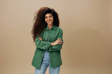 Mutlu, kendine güvenen, bronzlaşmış kıvırcık kıvırcık, sıradan şeyler giymiş, çapraz ellerde, pastel bej arka planda izole bir şekilde duran Latin kadın. Kameraya bak. Uzayı kopyala Mockup Banner. İyi teklif.