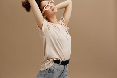 Güneş gözlüklü güzel kadın modern tarz bej arka plan pozu veriyor. Yüksek kalite fotoğraf