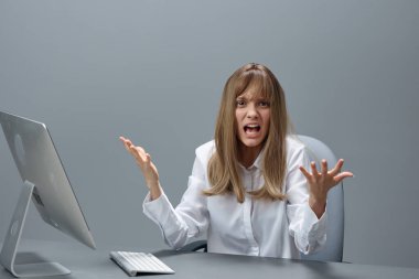 Sinirli sarışın iş kadını gri modern ofiste işyerinde oturan masaüstü bilgisayar açık ellerini kullanarak kritik bir hata yaptı. Uzaktan İş, Teknoloji ve Meslek Konsepti. Boşluğu kopyala